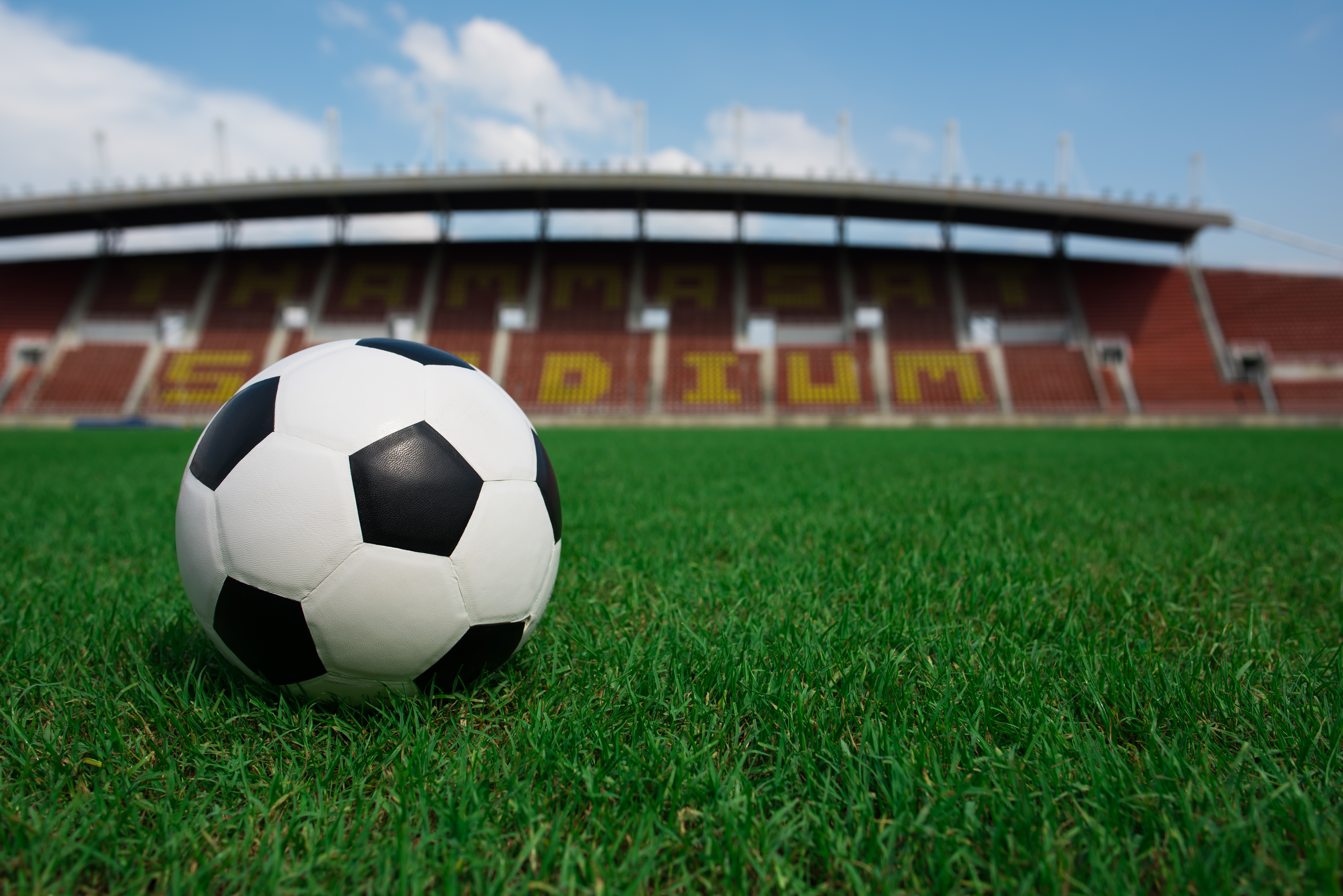 soccer-ball-on-grass-with-stadium-background.jpg